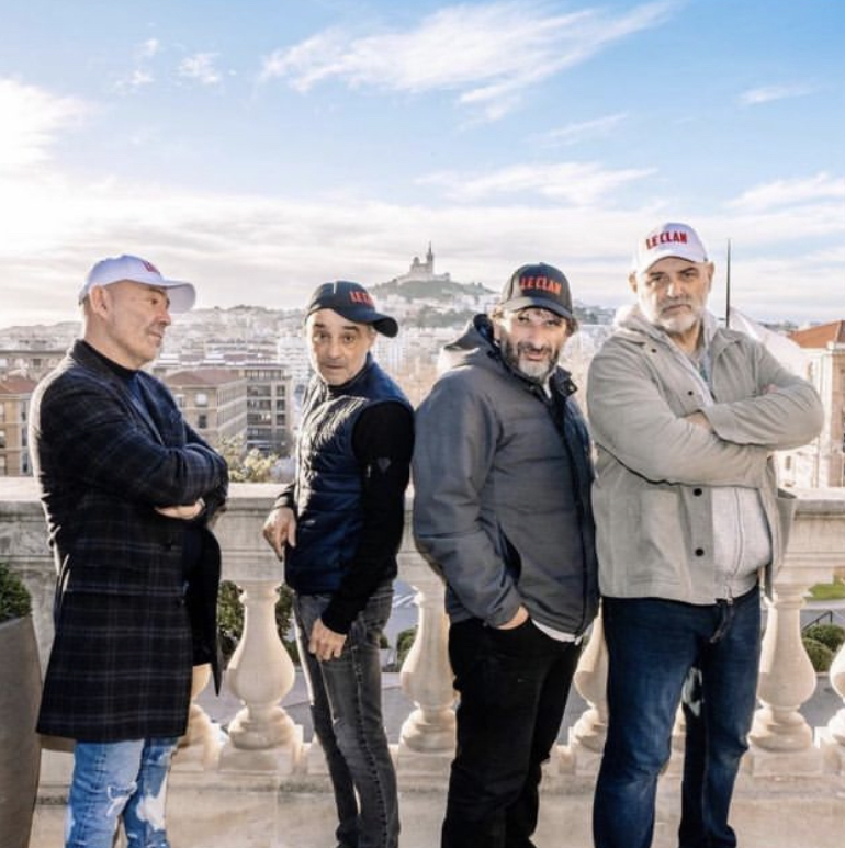 4 homme avec des casquettes le Clan posant devant notre-dame
